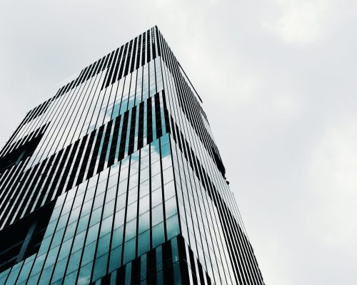 A low angle shot of a tall high-rise modern business building with a clear sky in the background