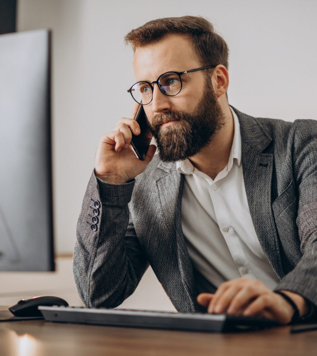 Young business man talking on phone and working on computer